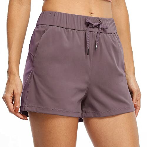 Woman wearing purple athletic shorts with drawstring.